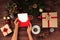 Christmas workplace top view. Girlâ€™s hands on the wooden table holding Christmas present. Christmas wreath