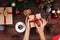 Christmas workplace top view. Girlâ€™s hands on the wooden table holding Christmas present. Christmas wreath, decorations