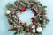 Christmas wreath or crown composition with fir garlands, spheres, sweets and candy cane on a blue background. Flat lay copy space