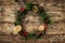Christmas wreath of Fir branches, cones, red decoration on wooden background with snowflakes.