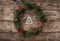 Christmas wreath of Fir branches, pine cones, berries and figurine of wood Christmas tree on rustic background.