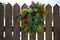 Christmas wreath with red berries hanging on wooden fence