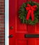 Christmas wreath on red paneled door with knob, lock and mail slot