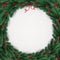 Christmas wreath of tree branches, berries on white background with lights, snowflakes.