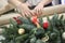 Christmas wrest with baubles and Woman wrapping modern Christmas gifts presents defocused