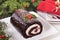 Christmas yule log cake on plate under tree with napkin