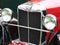 Chrome front grill headlamps and bumper of a Red Mg TC vintage sports car