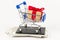 Chrome shiny shopping trolley on wheels with gift box on wallet with dollars on white background. selective focus
