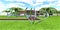 Chromed metal installation on a green meadow in the yard of a wonderful modern estate. The sidewalk is paved with red brick with a