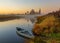 Chruch of Lady Day and wood boat in village of Dunilovo at autumn sunrise reflected in river