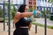 Chubby african woman exercising with dumbbell in public park outdoors, concentrated