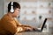 Chubby asian teenager using laptop and wireless headset, mockup