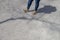 Chubby female wearing  tight blue jeans and golden white fashion sneakers waiting on a sidewalk with shadow and tree branch shadow