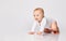 Chubby ginger baby boy in bodysuit, barefoot. He smiling, creeping on floor isolated on white background. Close up, copy space