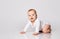 Chubby ginger baby boy in bodysuit, barefoot. He smiling, creeping on floor isolated on white background. Close up, copy space