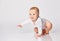 Chubby ginger little one in bodysuit, barefoot. He is sitting on floor isolated on white studio background. Close up, copy space