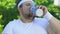 Chubby man drinking vitaminized beverage after workout restoring water balance