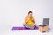 Chubby smiling plus size woman, sitting on sport mat at home, yoga mat watching movie on laptop, eating cookies. Online