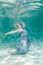 Chubby woman in grey evening long dress swimming underwater on her holidays and enjoy with relax