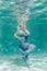 Chubby woman in grey evening long dress swimming underwater on her holidays and enjoy with relax