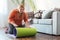 Chubby woman sport at home sitting rolling yoga mat joyful