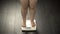 Chubby woman standing on home scales, normal weight, successful diet result