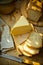 Chunk of cheese, loaf of sourdough bread on wood cutting board, linen napkin, rustic kitchen interior