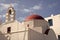 Church with bell tower and red dome in Mykonos, Greece. Chapel building architecture. White church on blue sky. Summer