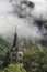 A church with a big clock in a mountain village in the Pyrenees with clouds behind it coming down the mountainside, church of