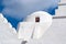 Church dome with small window in Mykonos, Greece. Chapel building architecture detail. White church on cloudy blue sky