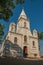 Church facade and belfry in front of a small cobblestone square with evergreen garden, in a sunny day at SÃ£o Manuel.