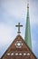 Church gable with Christian cross over a star of David with narrow slender spire in the background