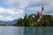 Church on an island on Bled lake with mountains and resort on the background