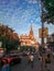 Church from long shot on sunny evening day with blue sky and busy road, people, platform, tree, car, vehicles