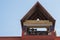 Church metal bells with emblems, located on roof of building under  canopy with system of rafters and brickwork on facade.