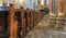 Church room of a medieval church with rows of wooden benches and coloured columns leading to the chancel with a magnificent