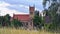 Church tower in village behind the  meadow with high grasses