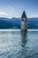Church under water, drowned village, mountains landscape and peaks in background. Reschensee Lake Reschen Lago di Resia.