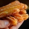 Churro Sticks in Hand, Churros Pastry, Fried Spanish Dessert, Churro Sticks Closeup, Copy Space