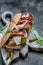 Ciabatta sandwich with prosciutto, sun-dried tomatoes, gherkins, parmesan and arugula. vertical image. top view