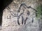 Cildren art in sandstone cave. Black carbon mammoth paint