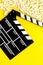 Cinema background. Film watching. Popcorn and clapperboard on yellow background top view copy space