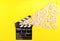 Cinema background. Popcorn and clapperboard on yellow background