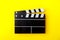 Cinema black clapperboard on yellow background. Modern cinematography, filmmaking