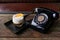 Cinema style photo of black dial phone and coffee cocktail with orange peel on wooden table. Luxury, creative background, Old fash