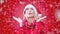 Cinemagraph of blond woman dressed as Santa Claus on red background and lots of snow