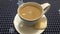 Cinemagraph -ed snow falling on the white cup of coffee with heart shaped cookie on a table with a checkered tablecloth