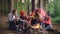 Cinemagraph loop - multiracial group of friends Caucasian and African American are sitting in wood around fire with