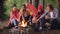 Cinemagraph loop - multiracial group of tourists is cooking food roasting marshmallow on open fire sitting in forest and