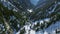 Cinematic aerial drone shot following train in snow mountain landscape.